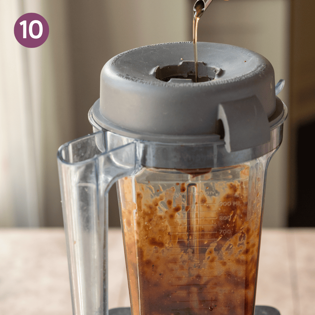 person pouring oil into blended vinaigrette in blender.