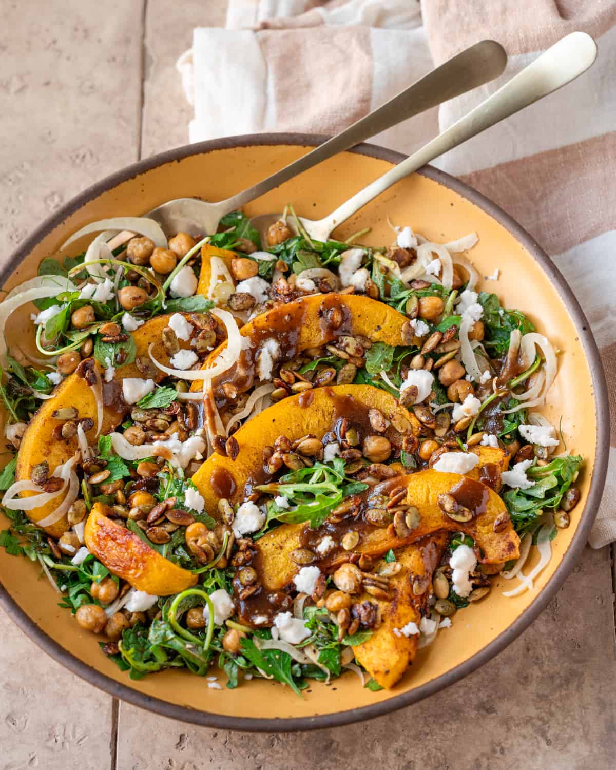 Side view of pumpkin salad on a yellow plate on a tan table.